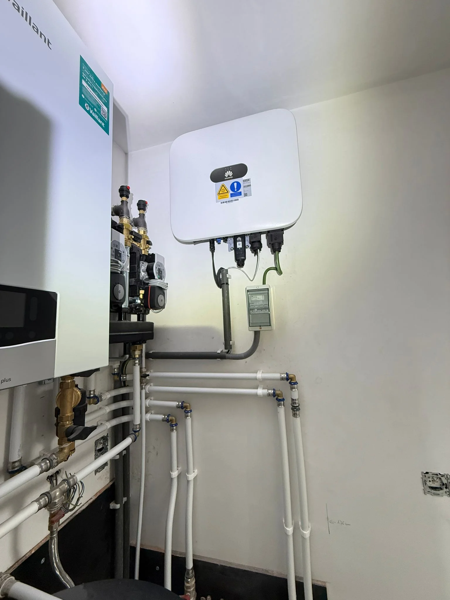 Binnendeel van een Vaillant-warmtepomp met pompgroepen en leidingen naast een omvormer in een technische ruimte