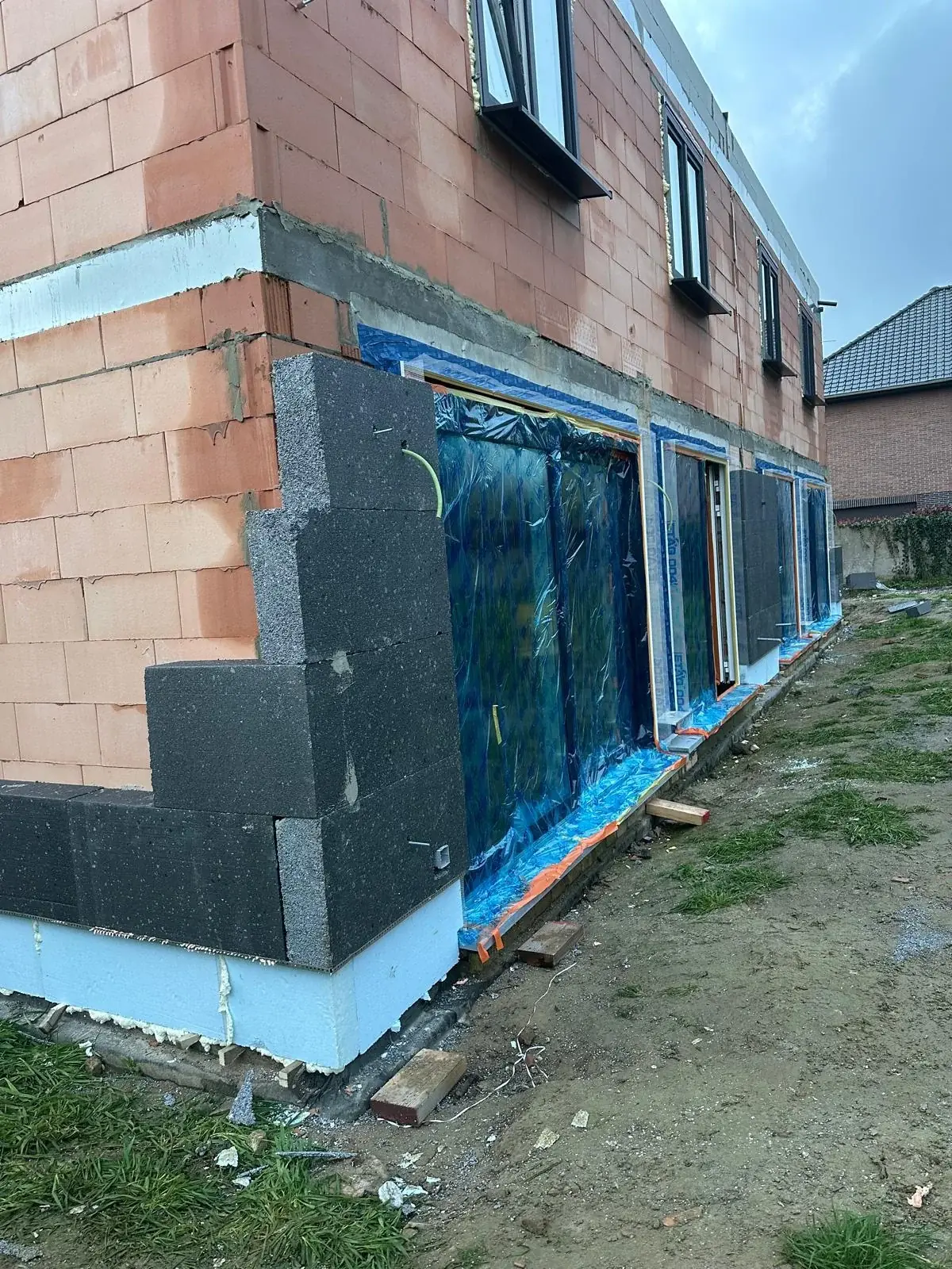 Bakstenen gevel in renovatie met nieuwe ramen en isolatie op de werf