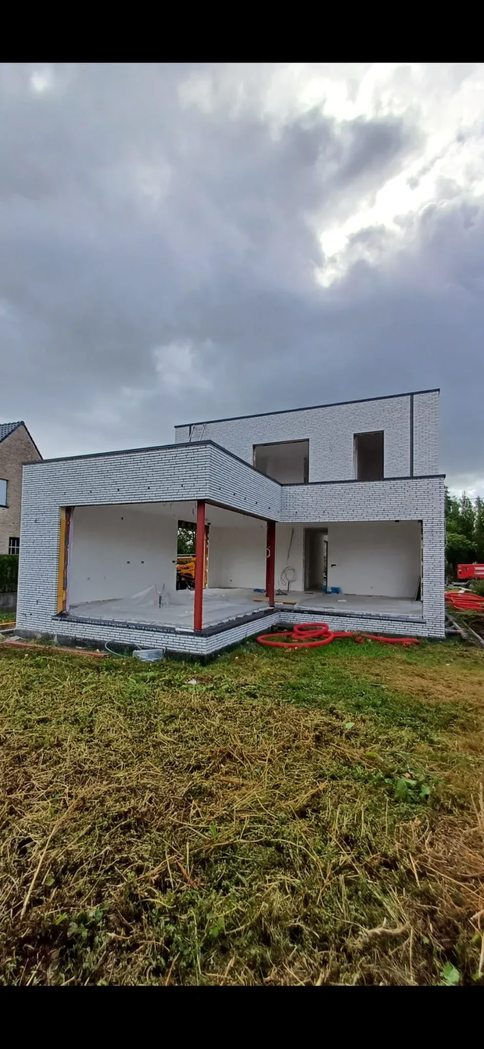 Woning in witte gevelsteen met open raamopeningen, klaar voor het plaatsen van het schrijnwerk